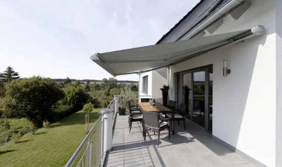 Moderne Terrasse mit Markise und Sitzbereich im Grünen